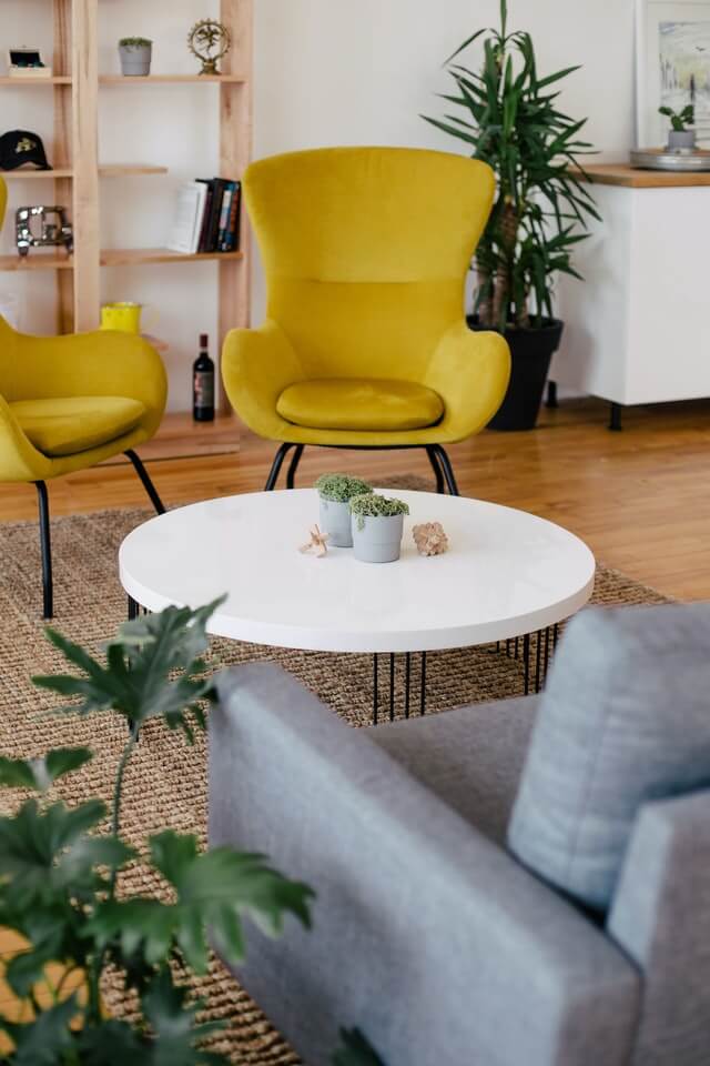 Cozy modern living room with yellow chairs and a white coffee table.