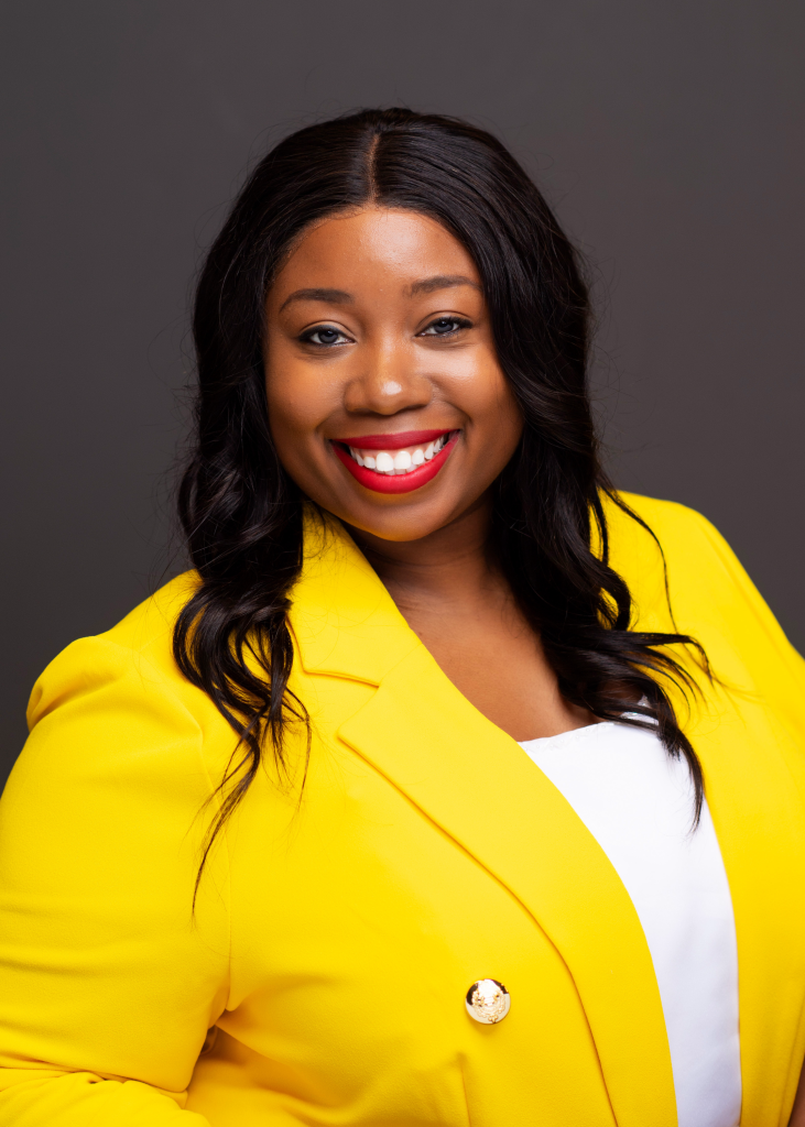 Confident woman in a bright yellow blazer smiling warmly.