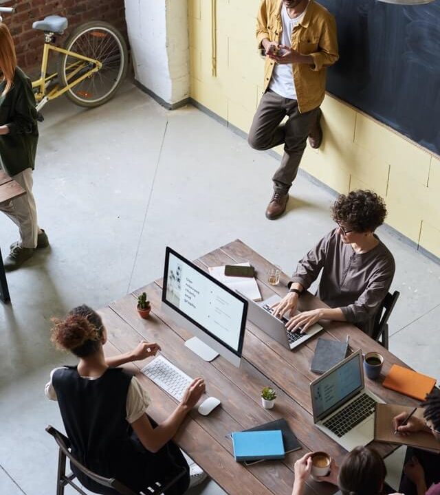 People working together in a modern office space with laptops and coffee.
